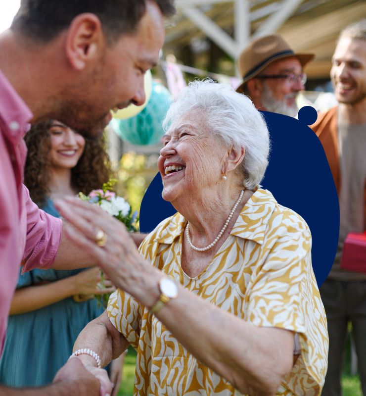 An elderly woman smiling at a man in a party